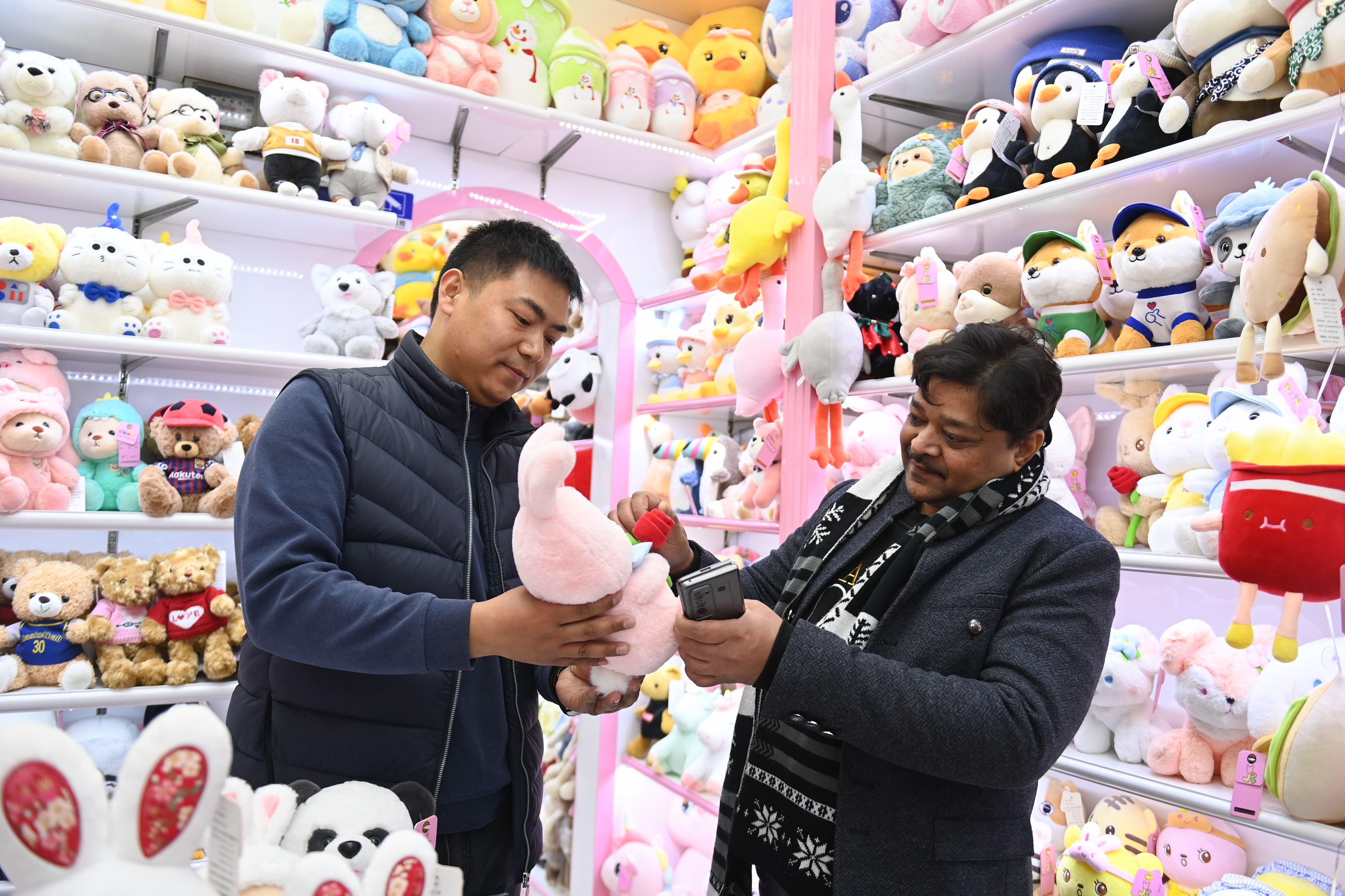 2023年2月2日，來自印度的客商（右）在義烏國際商貿(mào)城的一家玩具店鋪內(nèi)選購。